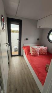 Schlafzimmer mit einem roten Bett und einem großen Fenster in der Unterkunft Houseboat Water Boy apartament pływający dom na wodzie łódź in Breslau