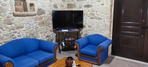 a living room with two blue chairs and a tv at Villa Margarita's farm, private pool in Maláthiros