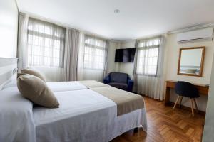 a hotel room with a bed and a desk and windows at Hotel Miramar Playa America Nigran in Nigrán