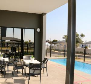 a patio with tables and chairs next to a pool at The Red Portrait at Carlswald in Midrand