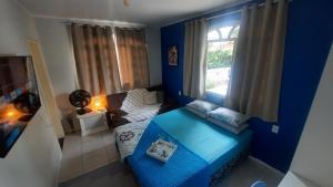 Suíte Azul com SmartTv, Cama Queen e Banheiro Privativo في إيتاجاي: غرفة معيشة زرقاء مع أريكة ونافذة