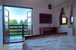 - une chambre avec un lit et un balcon avec une télévision dans l'établissement Cabana Plăieșul, à Tîrgu Neamţ