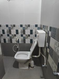 uma casa de banho com WC e azulejos na parede em Mysore Studio Rooms em Mysore