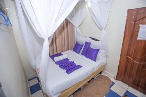 a bedroom with a canopy bed with purple pillows at Happy Springs Hotel & Accomodation in Kericho