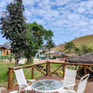um pátio com cadeiras, uma mesa e uma cerca em Hotel Pousada Bambuzal em Sana