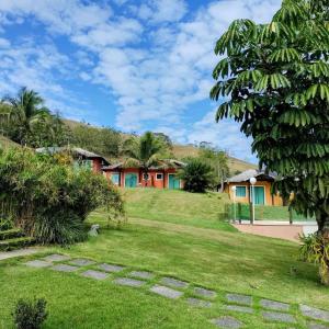 uma casa com um relvado verde e árvores em Hotel Pousada Bambuzal em Sana