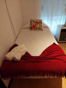 a bed with a red blanket and a pillow on it at Apartamento Orquídea in Ponta Delgada