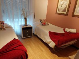 um quarto com duas camas e um vaso sobre uma mesa em Apartamento Orquídea em Ponta Delgada