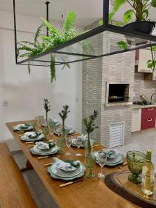 a long wooden table with plates and glasses on it at casa vô Minga in Penha
