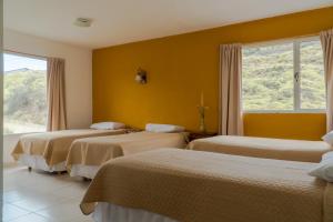 a hotel room with three beds and a window at Hosteria Alma de Patagonia in El Chalten