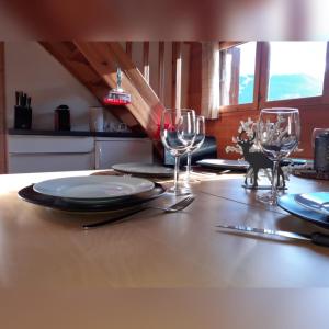 a table with plates and wine glasses on it at CHALET Indépendant Les Petits Yetis in Verchaix