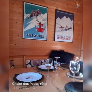 a table with wine glasses and posters on the wall at CHALET Indépendant Les Petits Yetis in Verchaix