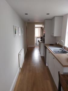 a kitchen with white cabinets and a wooden floor at No 2 New Buildings Morebattle in Morebattle