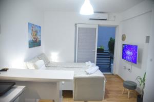 a white living room with a bed and a desk at Dekart 2 Apartment in Niš