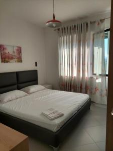 a bedroom with a bed and a window with curtains at Vala Mar apartment- A41 in Durrës