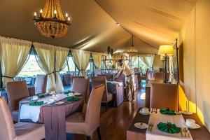 a restaurant with tables and chairs and a chandelier at Mutara Camp- Nanyuki in Nanyuki