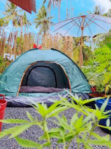 a green tent on the ground with an umbrella at Ganja Gardens Camping in Ban Nua