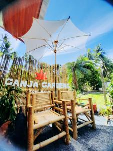 a group of chairs and an umbrella on a beach at Ganja Gardens Camping in Ban Nua