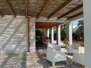 eine Terrasse mit weißen Stühlen und einer Holzdecke in der Unterkunft Villa Aloe in Menfi