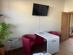 a room with a white table and two red chairs at DZ Appartements - Ferienwohnung mit Klimaanlage, Whirlpool und freiem WLAN - ruhige, zentrale Lage in Wittenberge in Wittenberge