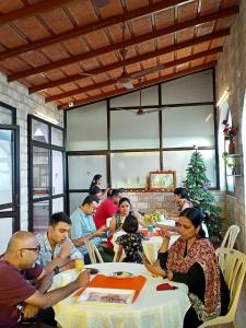 grupa ludzi siedzących przy stole w restauracji w obiekcie La Maison Pondichéry w mieście Puducherry
