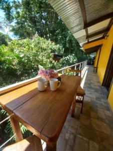 a wooden table on a balcony with two mugs on it at Cabinas Coconut Grove in Puerto Viejo