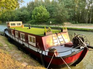 a house boat is docked in the water at Péniche Dondon - Gîte cocooning sur Canal du midi in Avignonet-de-Lauragais