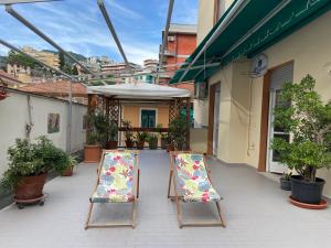 dwa krzesła ogrodowe siedzące na patio z roślinami w obiekcie SUNNY APARTMENT with big terrace w Rapallo