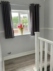 a window with a vase with red flowers in it at Luxury 3 Bedroom Apartment with Large Garden in Welling