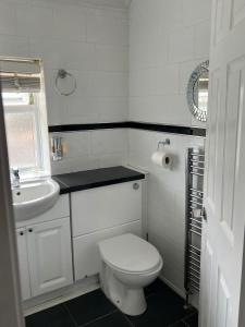 a white bathroom with a toilet and a sink at Luxury 3 Bedroom Apartment with Large Garden in Welling