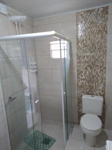 a bathroom with a toilet and a glass shower at Pousada JOSHUA in Penha