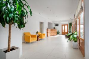 a hallway with yellow chairs and a potted plant at Anamnesis City Spa in Fira