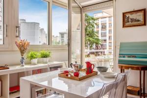 uma sala de jantar branca com uma mesa e janelas em Superb apartment with balcony - Boulogne-Billancourt - Welkeys em Boulogne-Billancourt