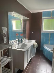 ein Badezimmer mit zwei Waschbecken, einem Spiegel und einer Badewanne in der Unterkunft Gîte de la sablière in Courlay