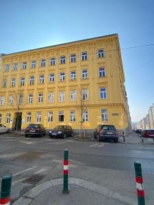 un bâtiment jaune avec des voitures garées devant lui dans l'établissement Trendy apartment near Schloss Schönbrunn, à Vienne