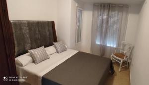 ein Schlafzimmer mit einem Bett, einem Fenster und einem Stuhl in der Unterkunft TU CASA en Benetússer , VALENCIA in Benetúser