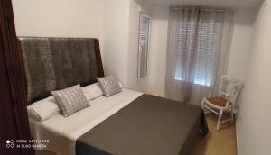 a bedroom with a bed and a window and a chair at TU CASA en Benetússer , VALENCIA in Benetúser