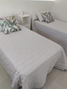 een slaapkamer met 2 bedden en witte lakens bij A Casa do Lago in Pontevedra