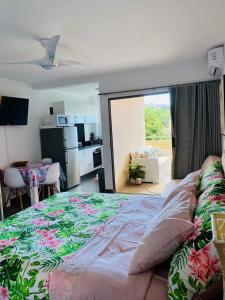 a bedroom with a large bed and a kitchen at Tehautahi Cozy Lodge in Papeete