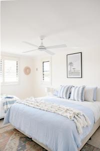 a white bedroom with two beds and a ceiling at Casa Keys Shoal Bay in Shoal Bay