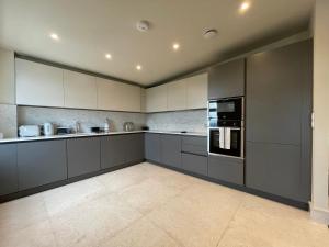 a large kitchen with gray cabinets and appliances at luxurious, 2 bed, 2 bath penthouse apartment in highly desirable Chigwell in Chigwell