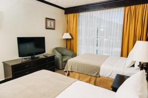 Habitación de hotel con 2 camas y TV de pantalla plana. en Plaza Hotel and Suites en San Salvador