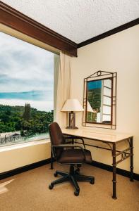 een kantoor met een bureau, een stoel en een raam bij Plaza Hotel and Suites in San Salvador