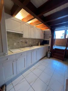 cocina grande con armarios blancos y ventana en Rare 2 bedroom with private beach on Lake Annecy en Doussard