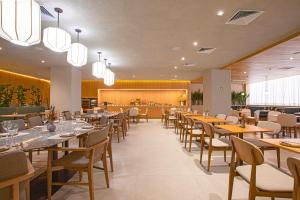 a restaurant with tables and chairs and a bar at QOYA Hotel Curitiba, Curio Collection by Hilton in Curitiba