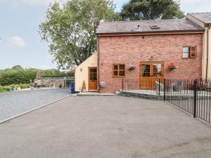 a brick house with a gate and a driveway at Ash Farm Cottage in Holywell