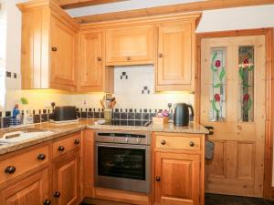 uma cozinha com armários de madeira e um fogão em Ash Farm Cottage em Holywell