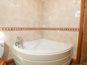 La salle de bains est pourvue d'une baignoire blanche et de toilettes. dans l'établissement Ash Farm Cottage, à Holywell 21 autres photos