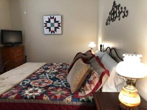 a bedroom with a bed with a quilt and a tv at The Farmhouse at Wolfehaven in Asheville