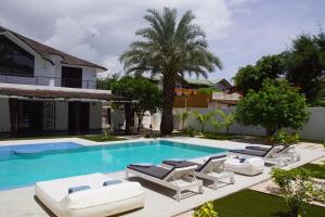 une piscine avec des chaises longues et une villa dans l'établissement Au Paradis de Jeanne, à Ngaparou